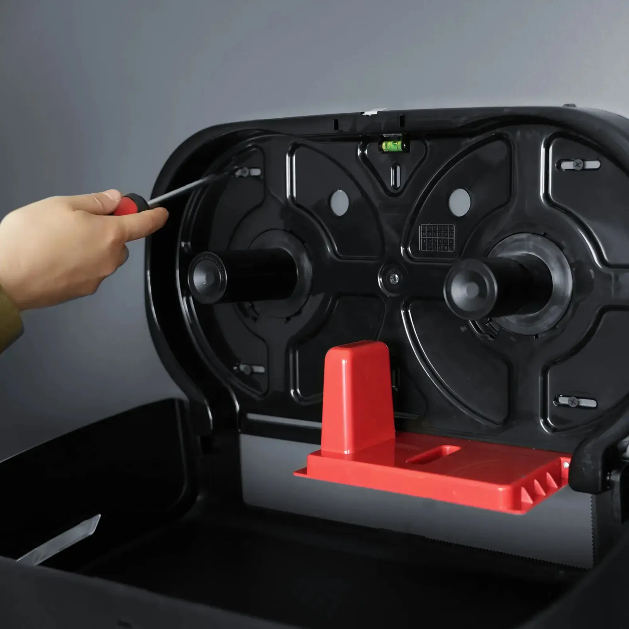 SEMYtop Maxi Jumbo Toilettenpapierspender für 2 Rollen bis Ø 23 cm, geöffnete Innenansicht mit zwei Rollenaufnahmen, roter Abreißkante und Hand bei der Montage