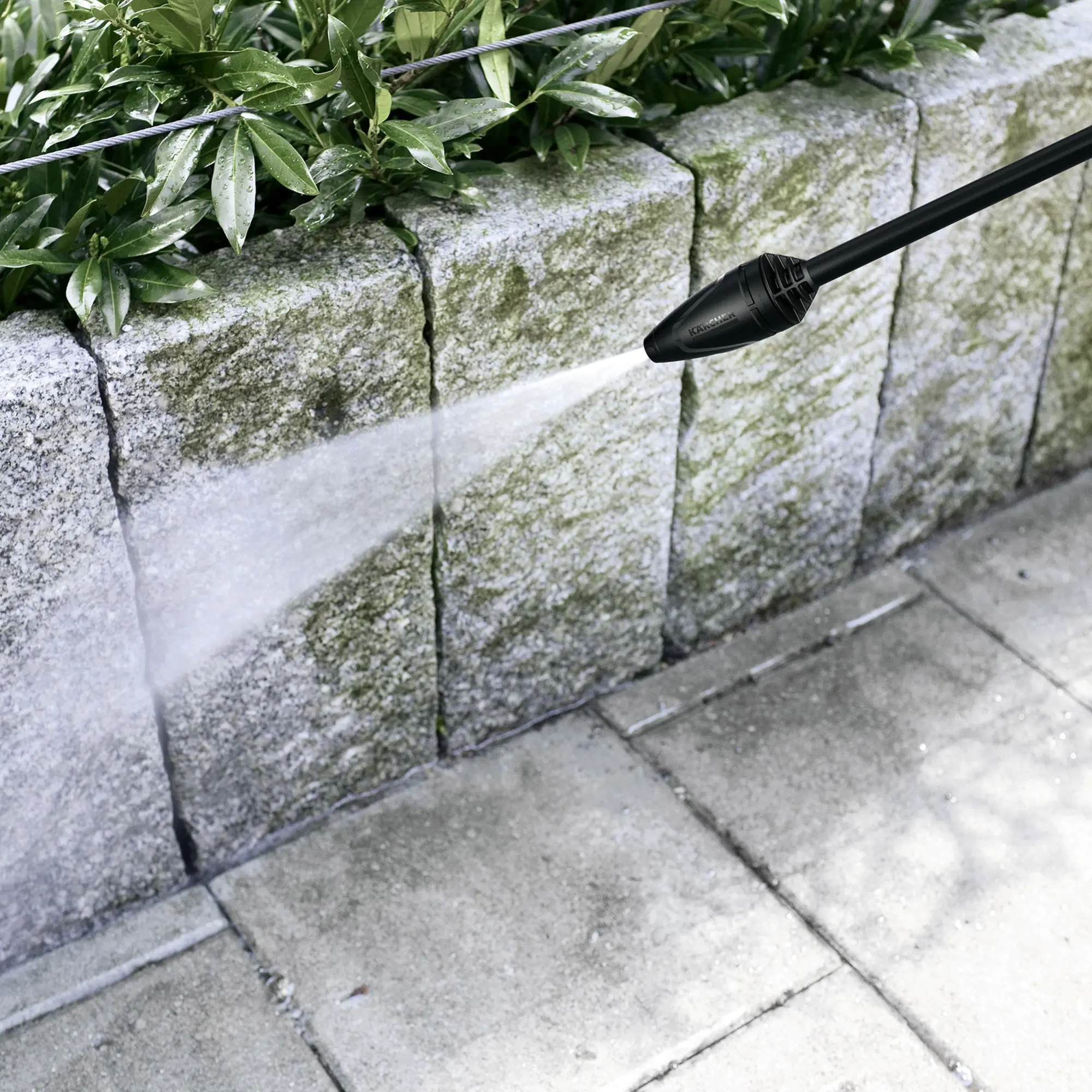 Kärcher K 5 Power Control Flex Home Hochdruckreiniger reinigt mit starkem Wasserstrahl eine vermooste Steinmauer und Terrassenplatten, Artikelnummer 1.324-553.0