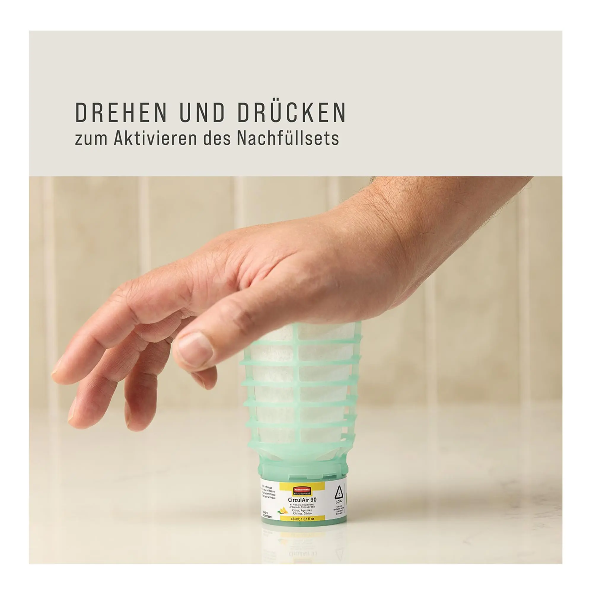 Rubbermaid CirculAir 90 Duftspender Nachfüllset von Rubbermaid, Hand zeigt Aktivierung des Nachfüllsets durch Drehen und Drücken für frischen Raumduft