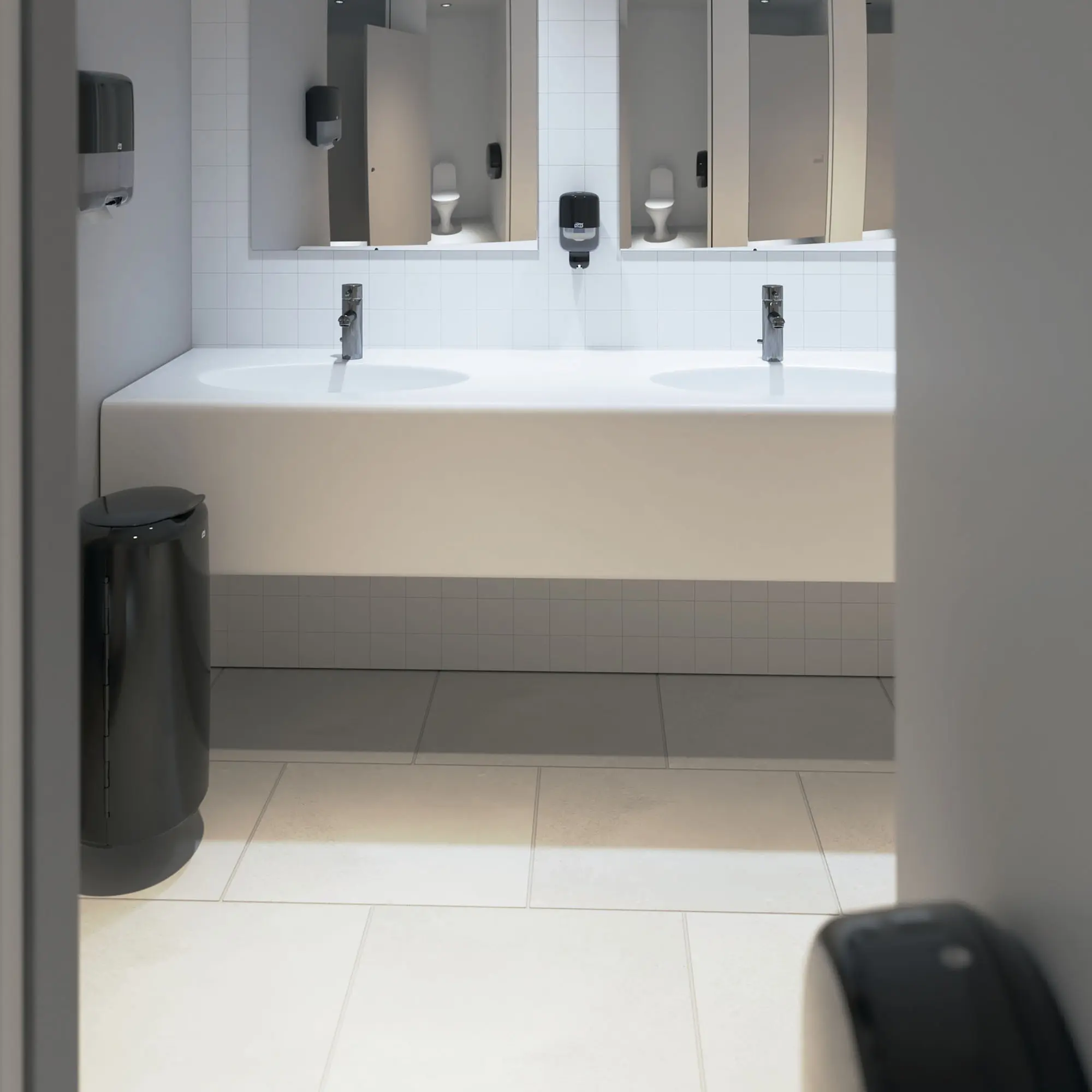 Tork Elevation Toilettenpapierspender Midi Jumbo T1 in modernem, hellen Waschraum mit Doppelwaschtisch und weiteren Tork Spendern, Artikelnummer 554008